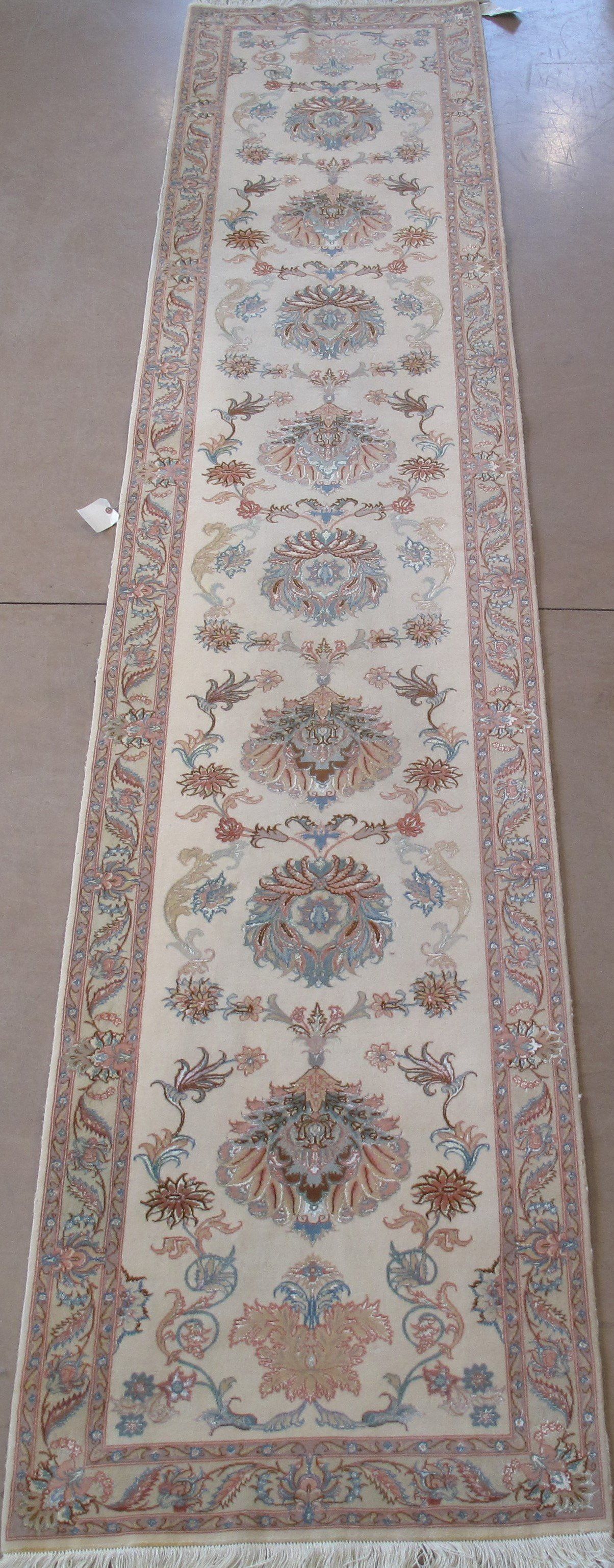 A long white rug with a floral pattern is sitting on a concrete floor.
