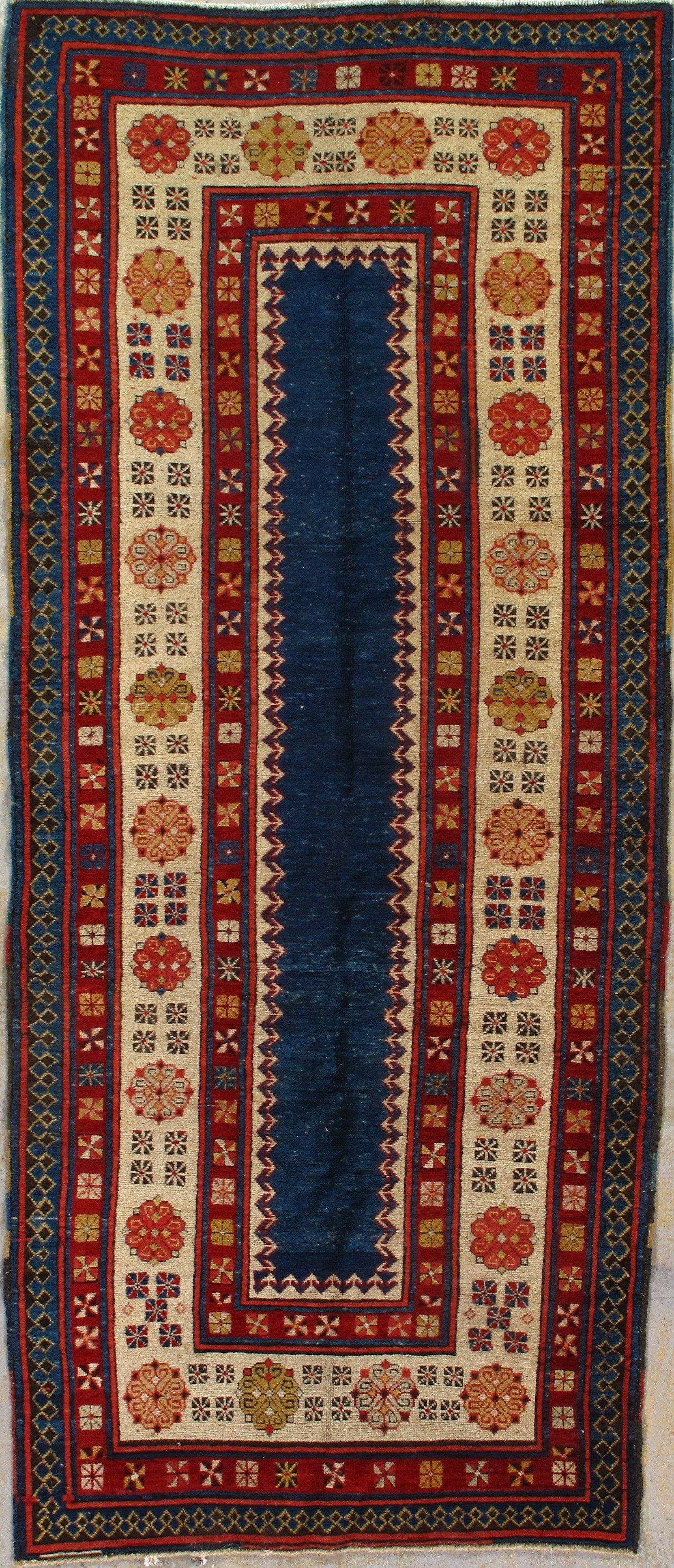 A rug with a blue border and flowers on it is sitting on a table.