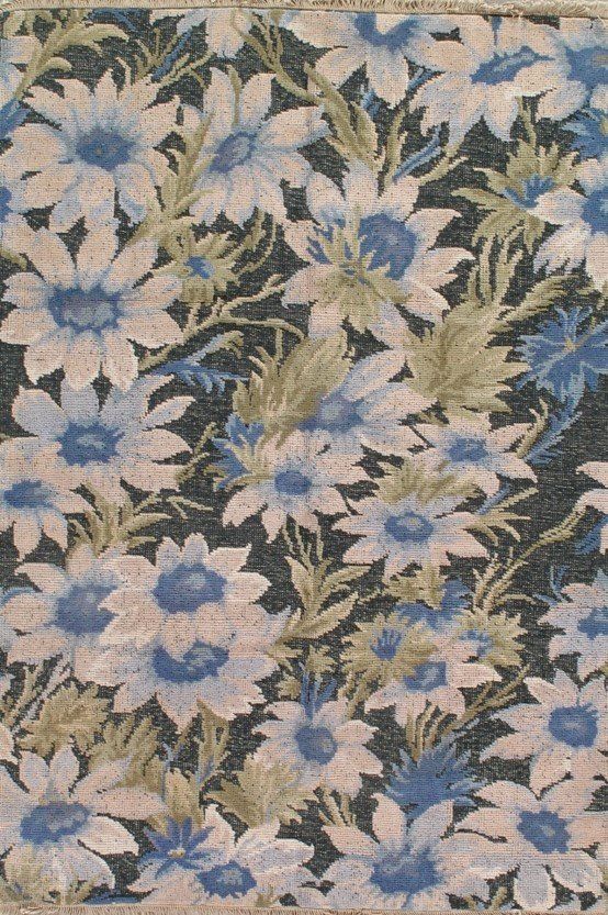 A close up of a rug with blue and white flowers on a black background.