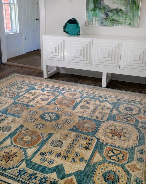 A rug is sitting on the floor in a living room next to a dresser.