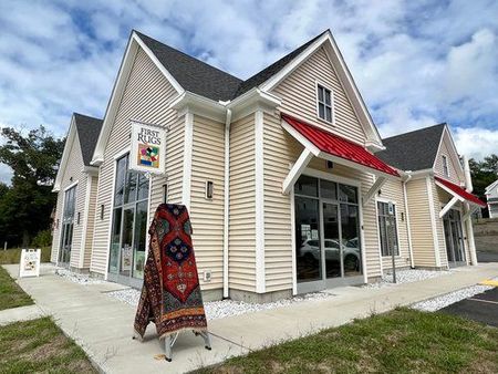 A large house with a red awning and a rug on the sidewalk in front of it.