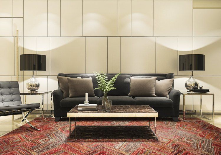 A living room with a black couch , coffee table , chair and rug.