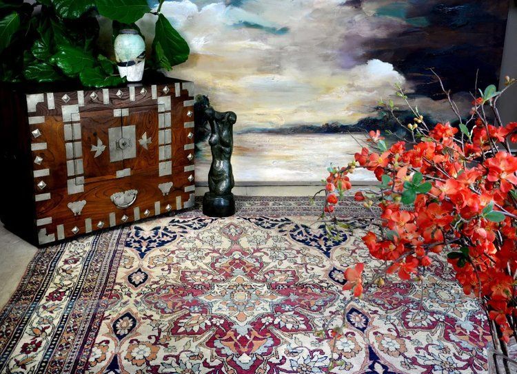 A rug is on the floor in front of a painting