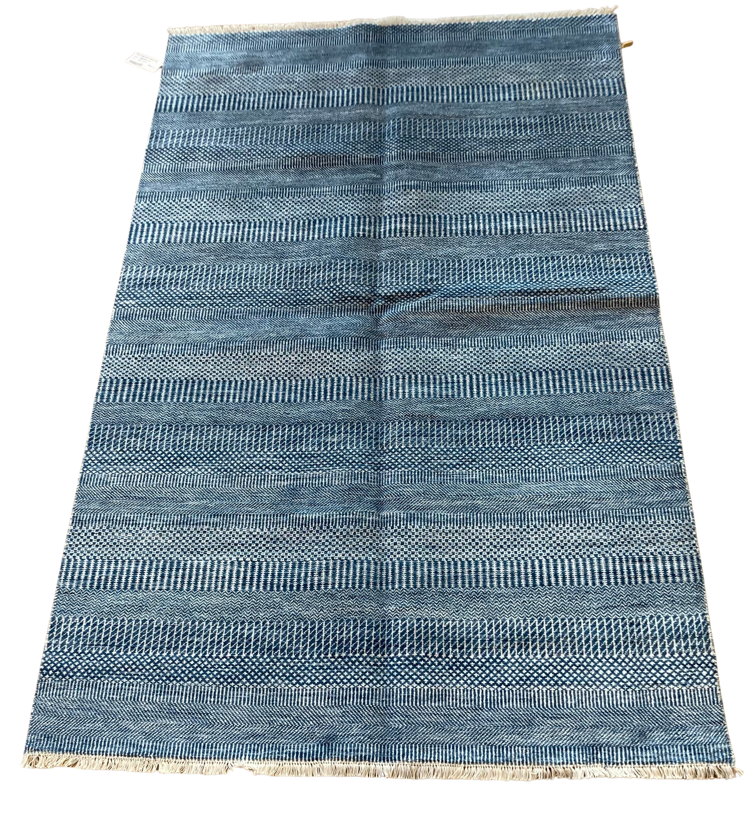 A blue rug with a pattern on it is sitting on a white surface.