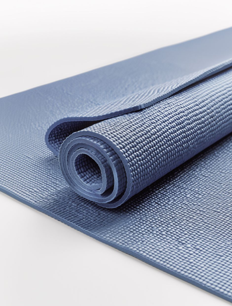 Rolled gray yoga mat with textured surface on a light background