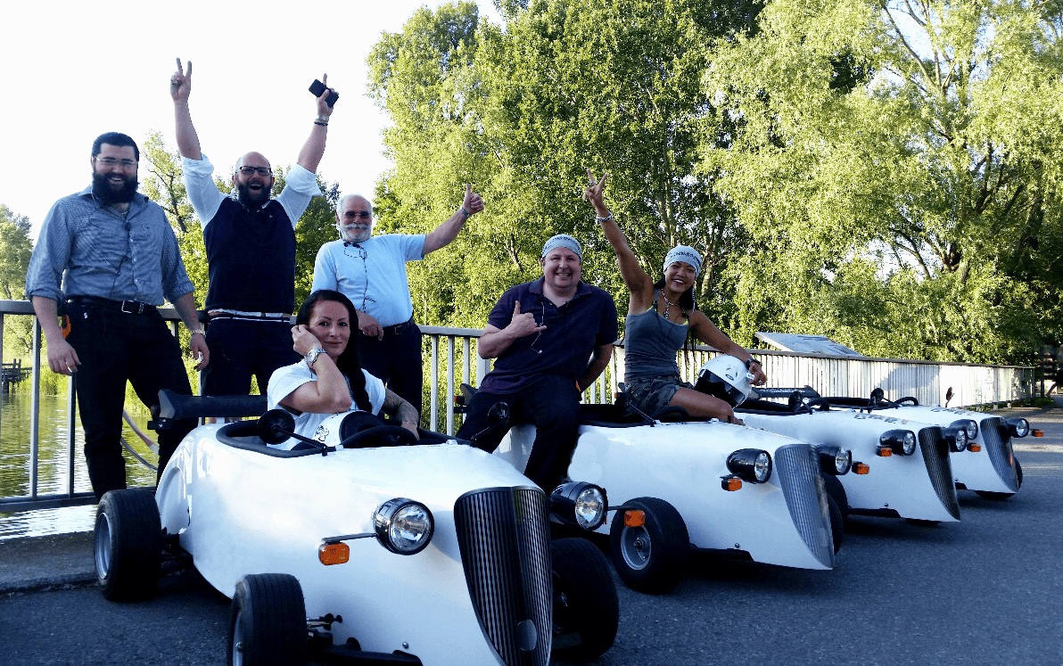 Lachende Teilnehmer mit Hotrods im Wald