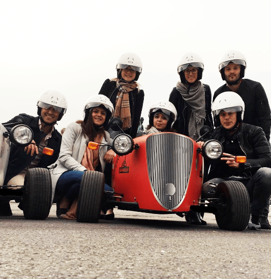 Gruppe von Touristen posieren vor rotem HotRod