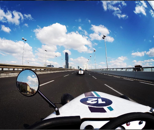 Hotrod beschleunigt auf leerer Straße mit Donaubrücke im Hintergrund