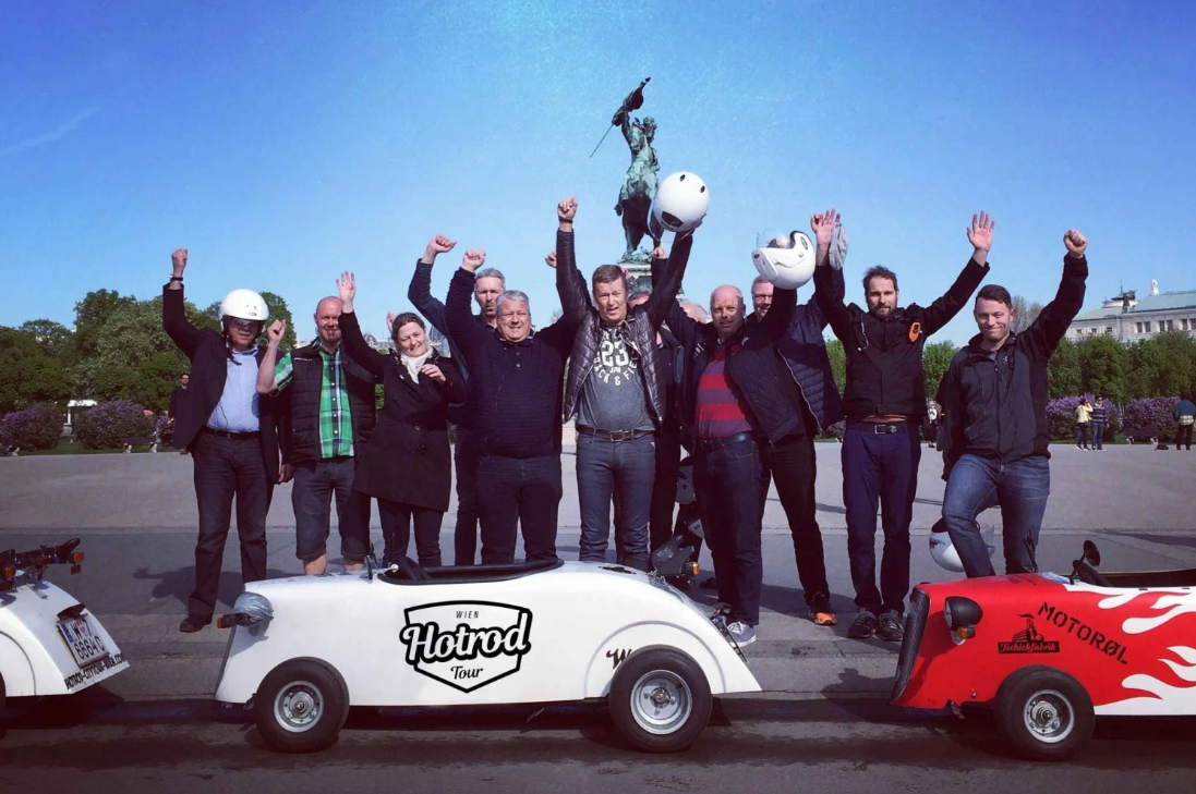 Gruppe mit gebrandeten Helmen vor den Hotrods – Firmenincentive in Wien