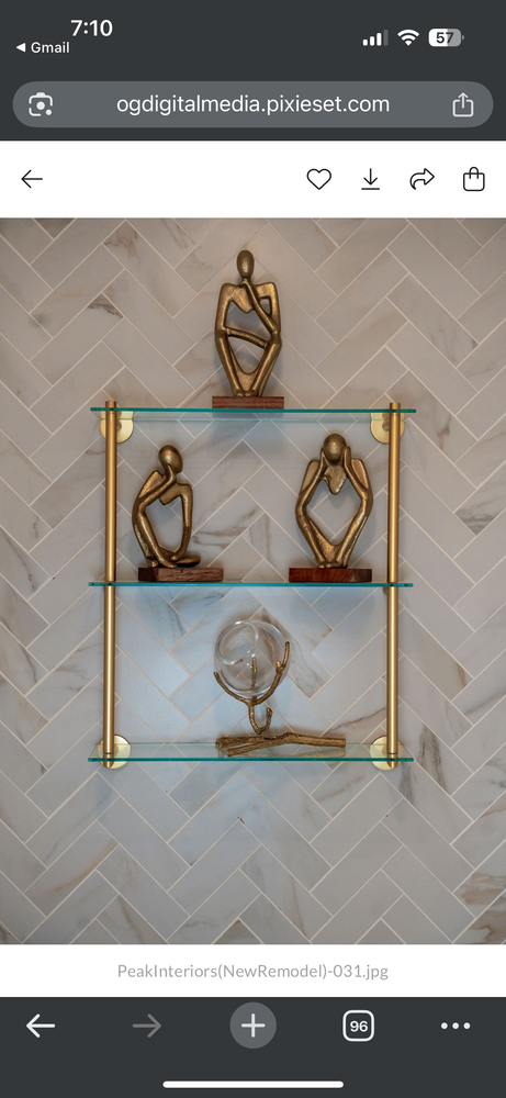 Gold and glass wall shelf with decorative sculptures against a tiled wall