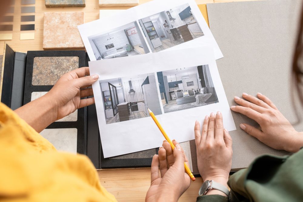 Hands reviewing architectural design sketches on a desk with a pencil and tablet
