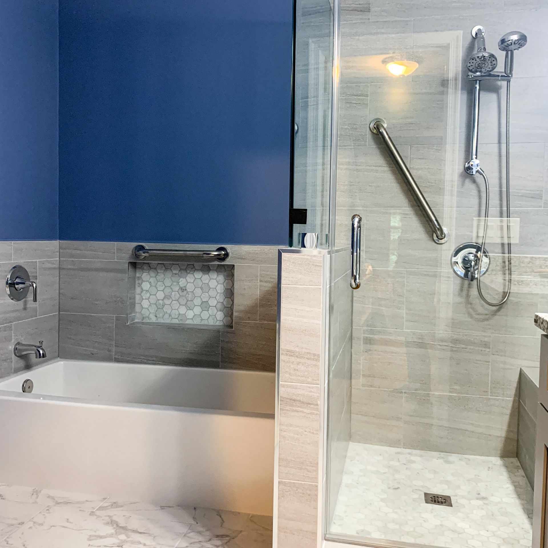 Accessible bathroom with a tub and shower. Features include grab bars, a low threshold shower, and neutral tile.