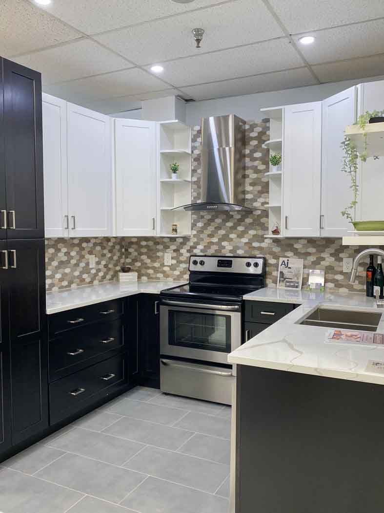 Modern kitchen with black and white cabinets, stainless steel appliances, and gray tile floor.