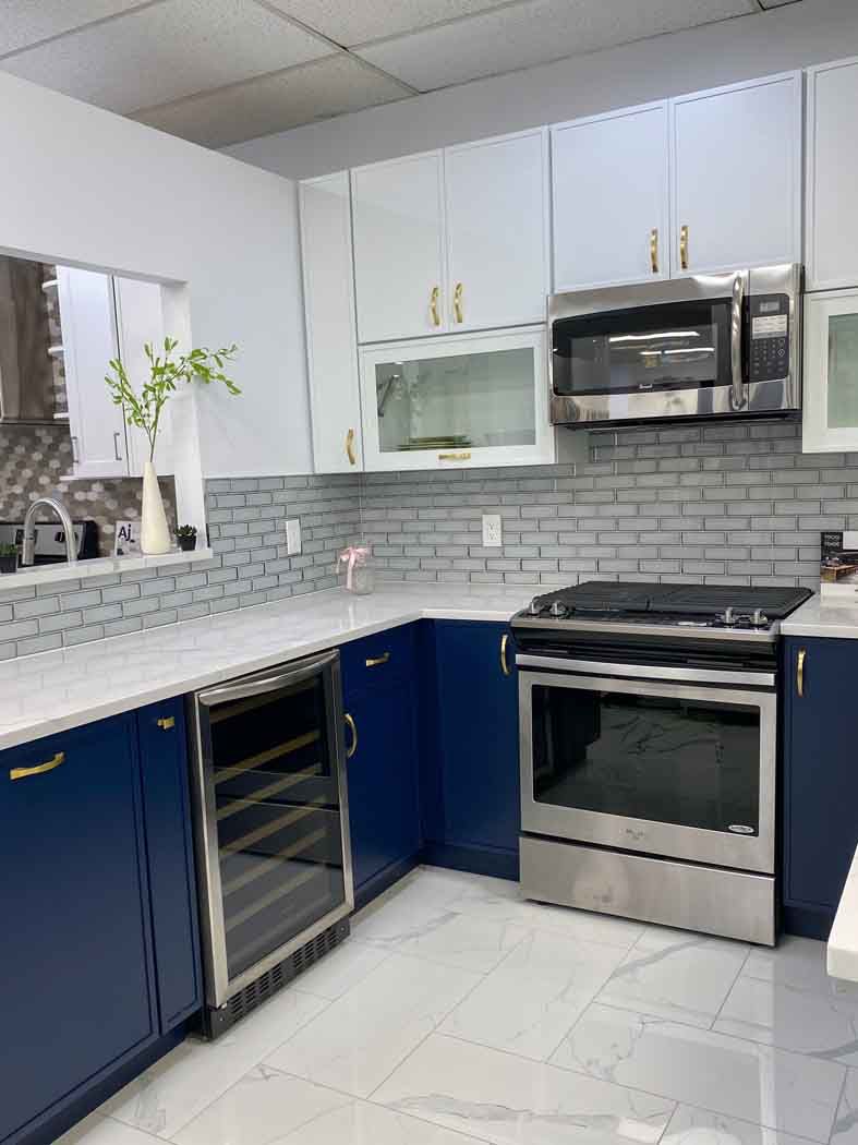 Modern kitchen with navy blue and white cabinets, stainless steel appliances, and white countertops and tile.