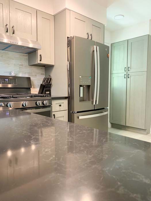 A modern kitchen featuring gray cabinetry, stainless steel appliances, and a gray countertop.