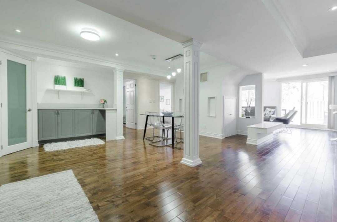 Spacious, bright interior with hardwood floors. Features a dining area, a seating area, and a built-in gray cabinet area.