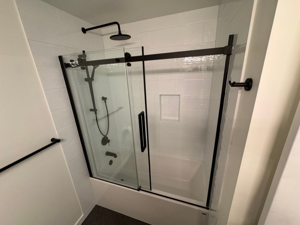 A bathroom with a sliding glass shower door and a shower head.