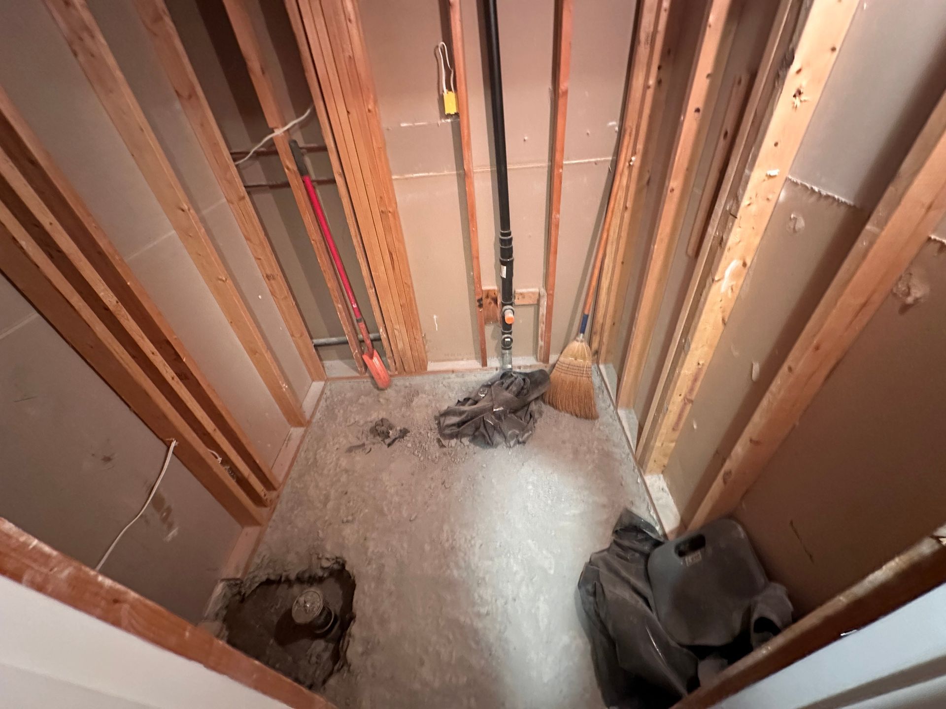 A bathroom under construction with a mop on the floor
