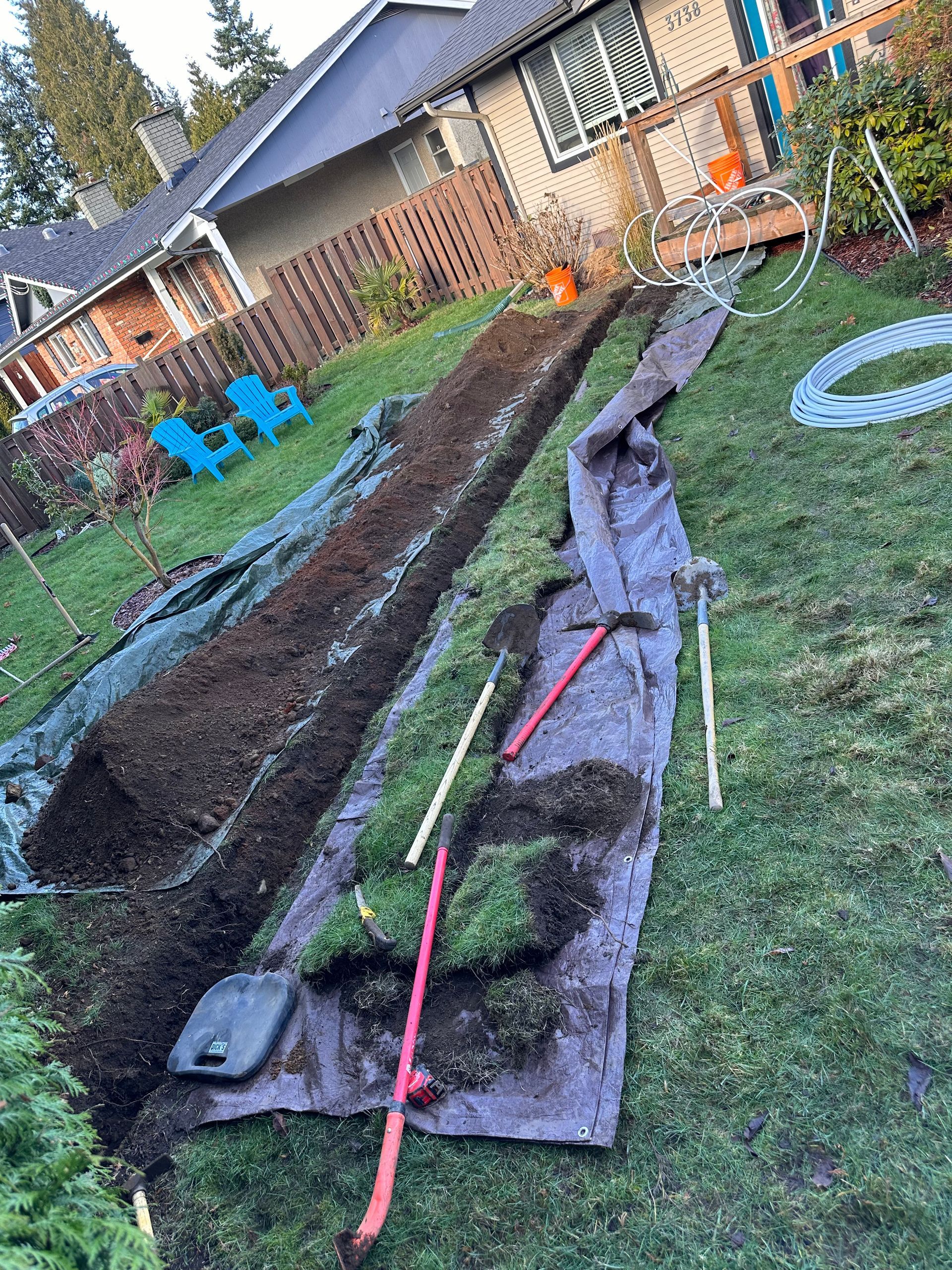 A hose is being installed in a yard next to a house.