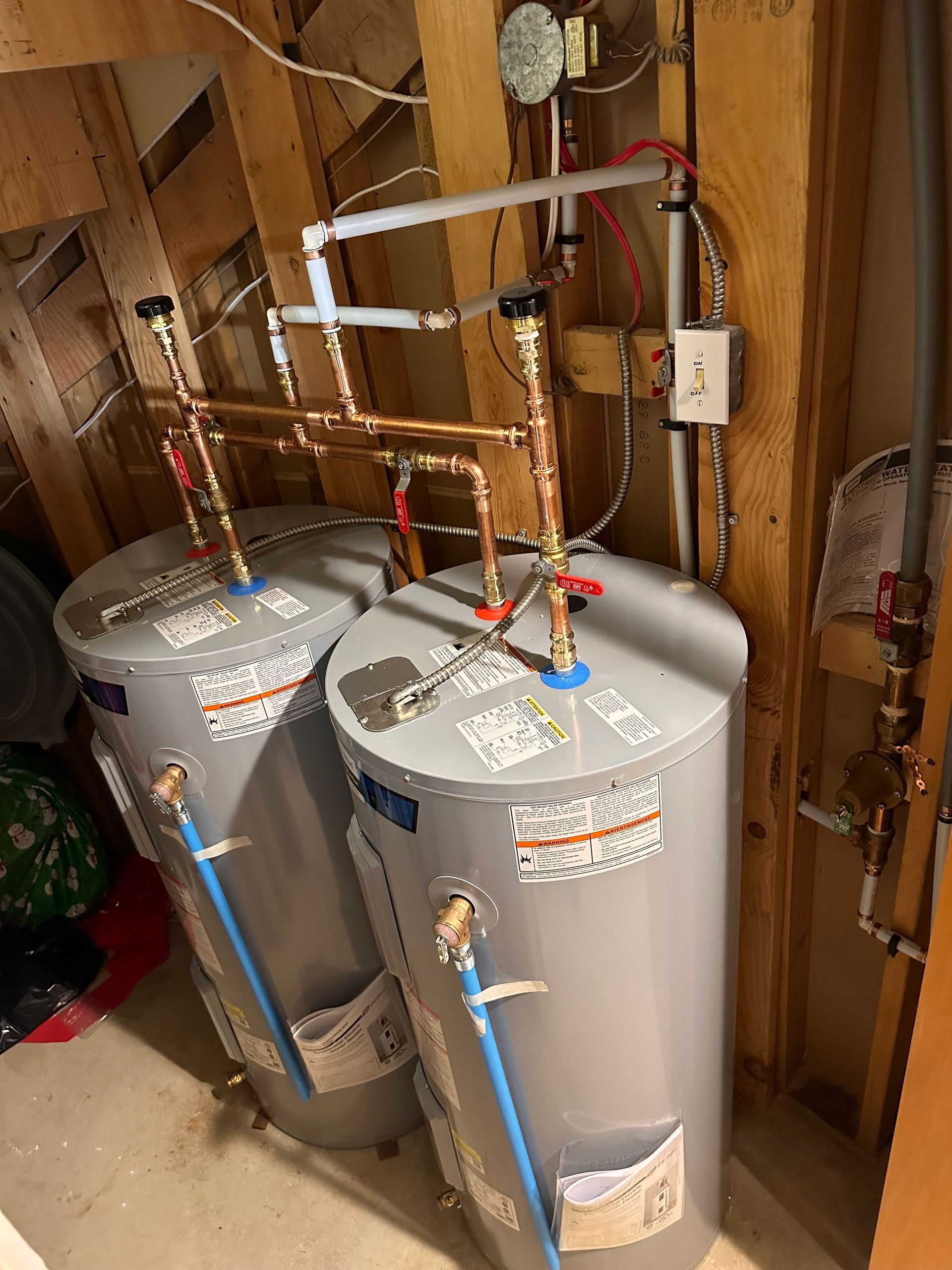 Two water heaters are sitting next to each other in a room.