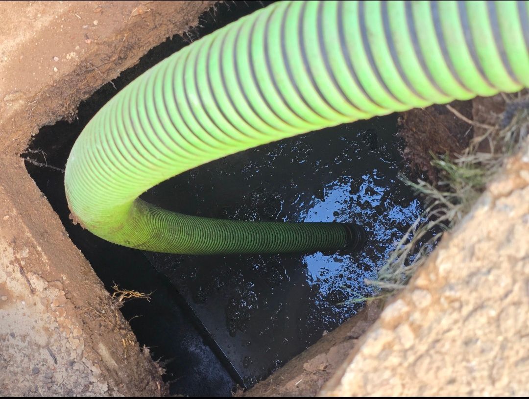 Green hose in a square opening filled with dark liquid.