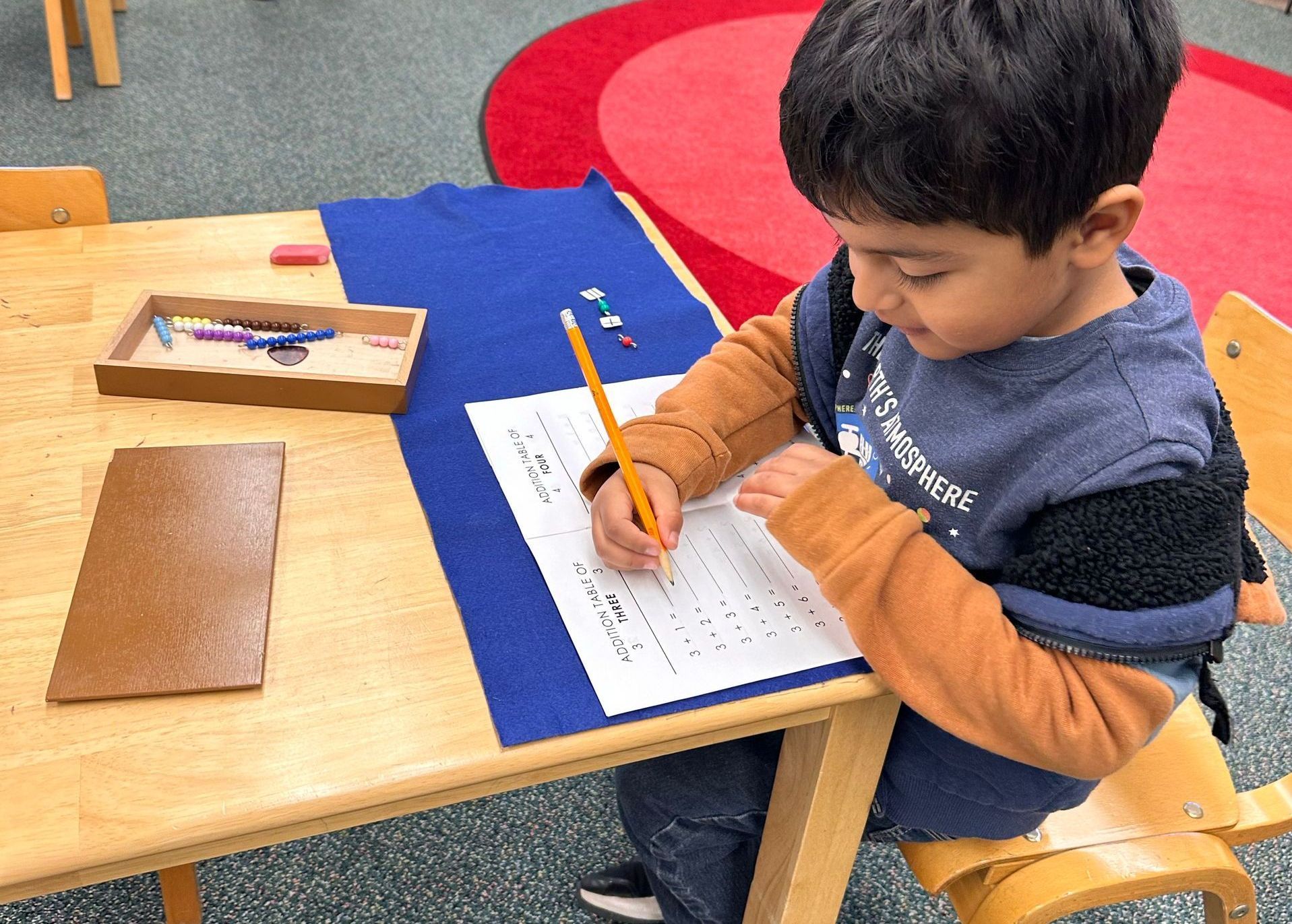 Montessori child in classroom drawing