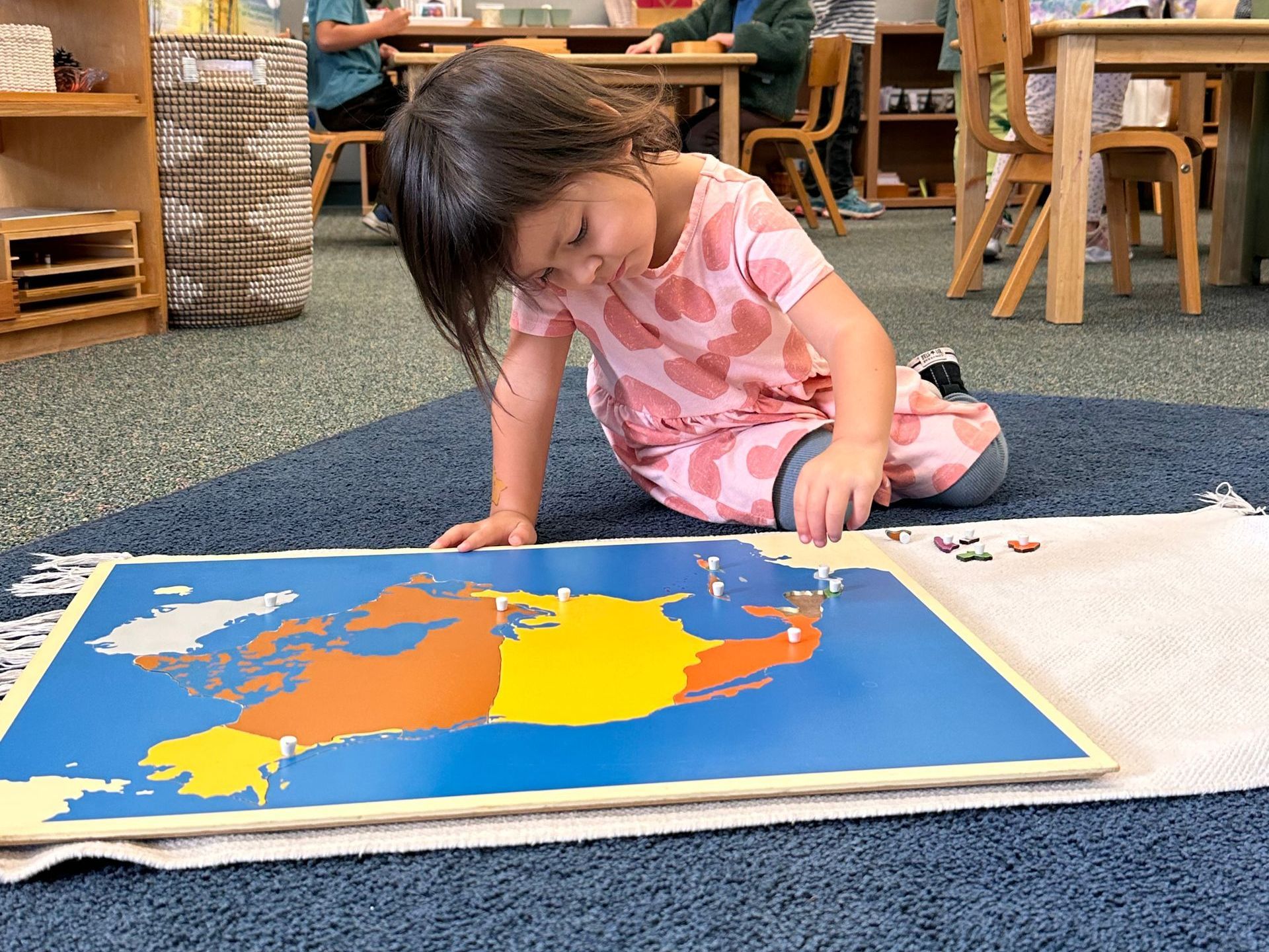Montessori child working with a map puzzle