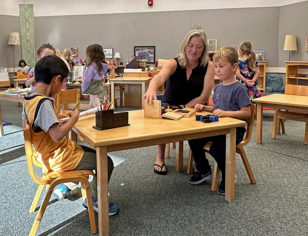 Montessori guide and child working in the classroom