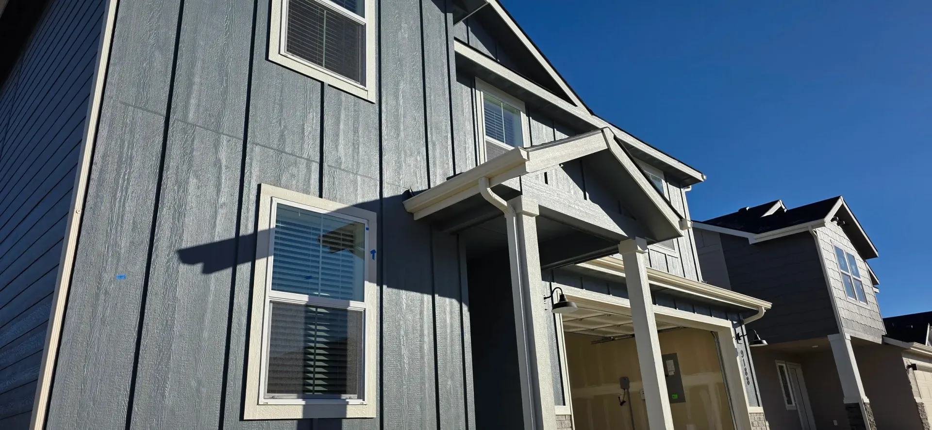 Gray houses with white trim against a bright blue sky.