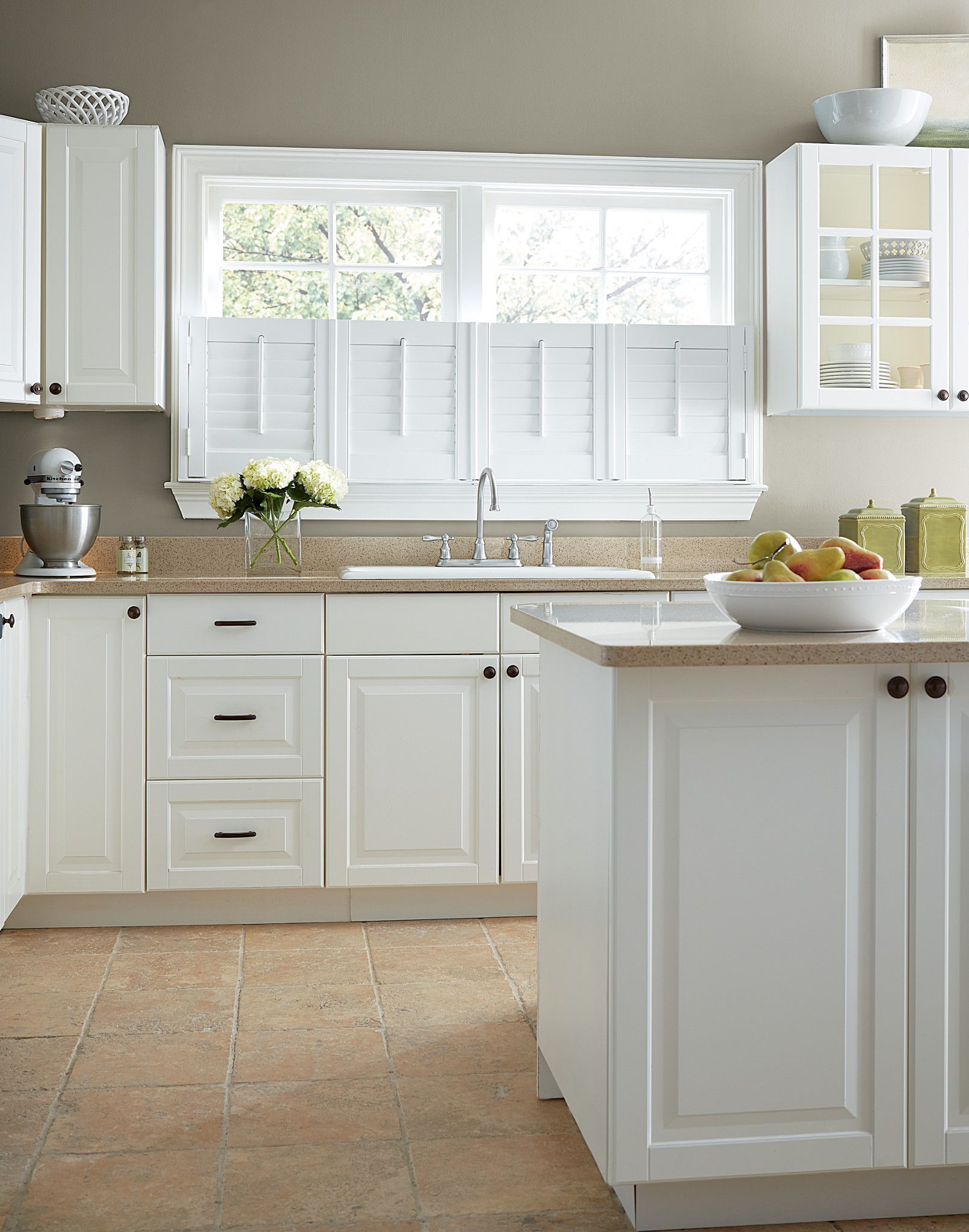 White kitchen with granite countertops, cabinets, and a window with shutters.
