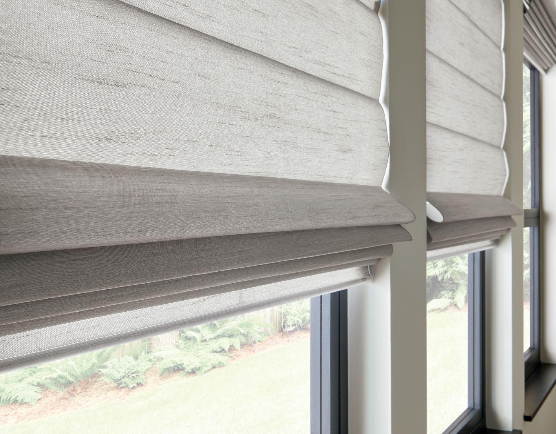 Gray roman shades partially covering windows, outdoors visible.