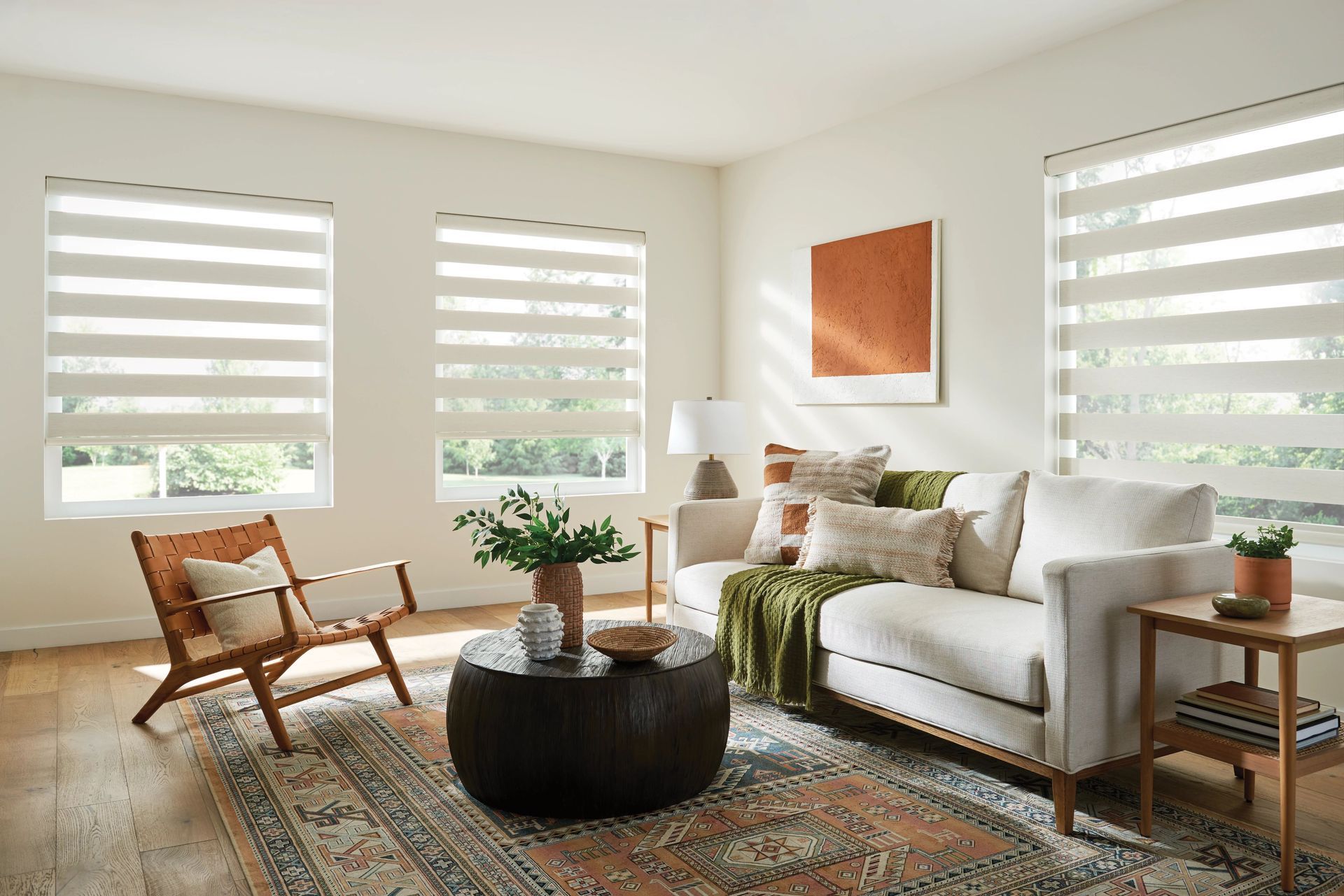 Living room with a white sofa, a wooden chair, and windows with layered blinds.