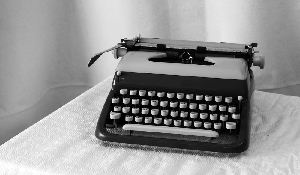 A black and white photo of an old typewriter on a table