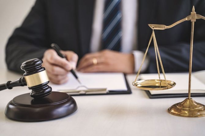 A judge is sitting at a desk with a gavel and scales of justice.