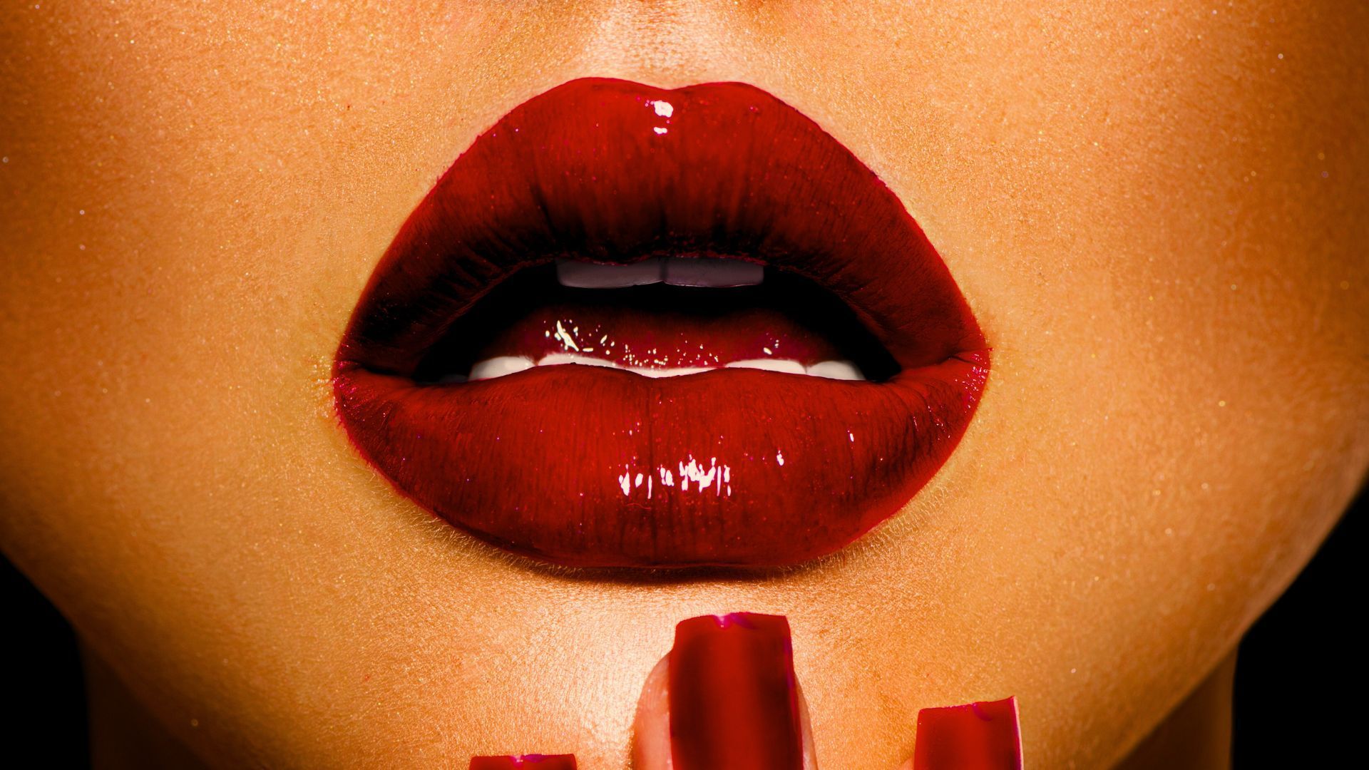 A close up of a woman 's red lips and red nails.