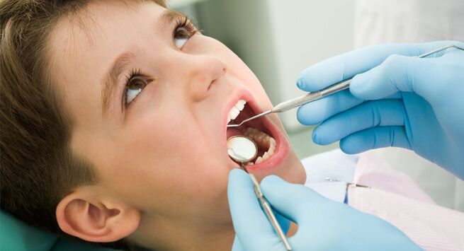 A young boy is getting his teeth examined by a dentist.