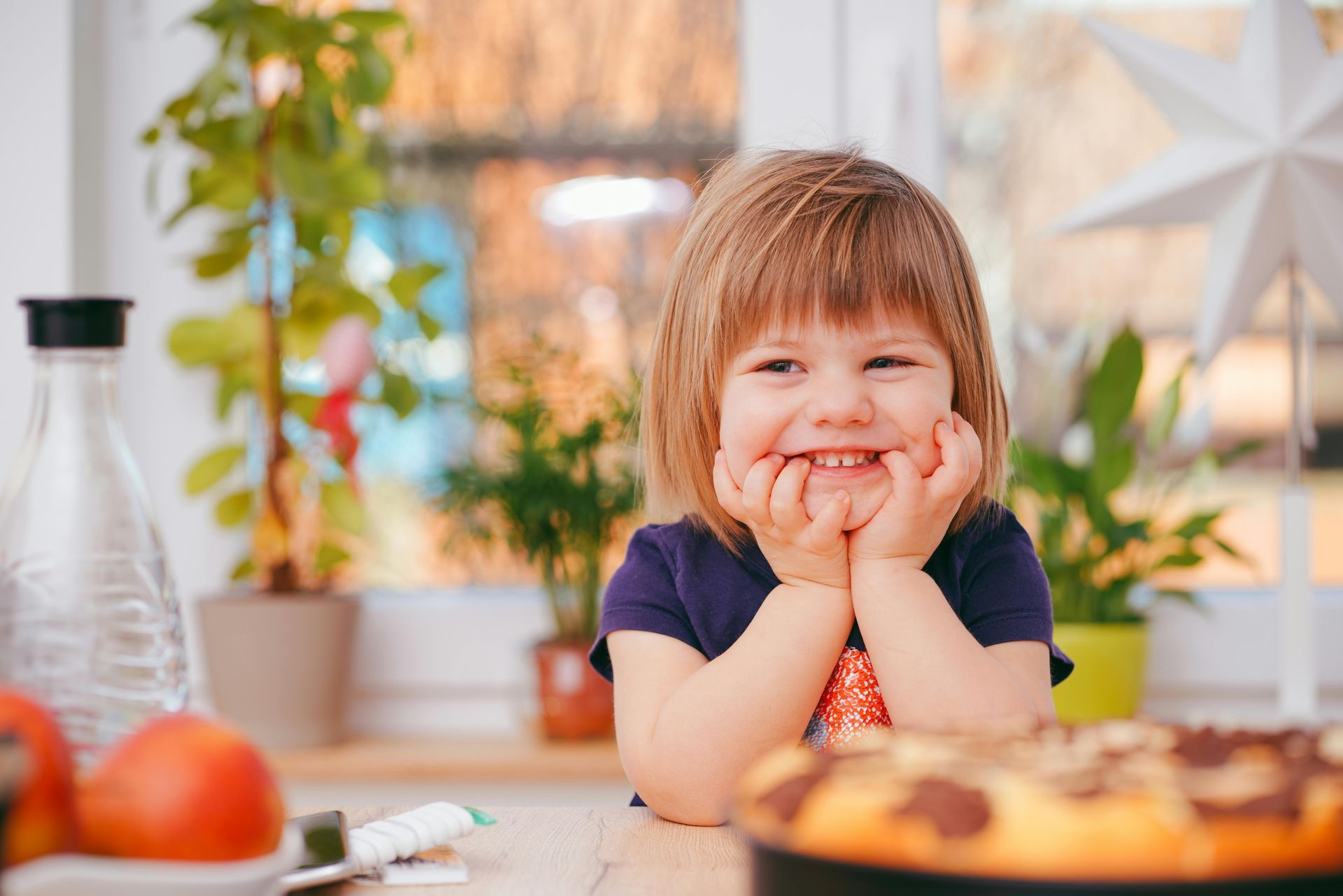 A little girl is sitting at a table with a cake in front of her.