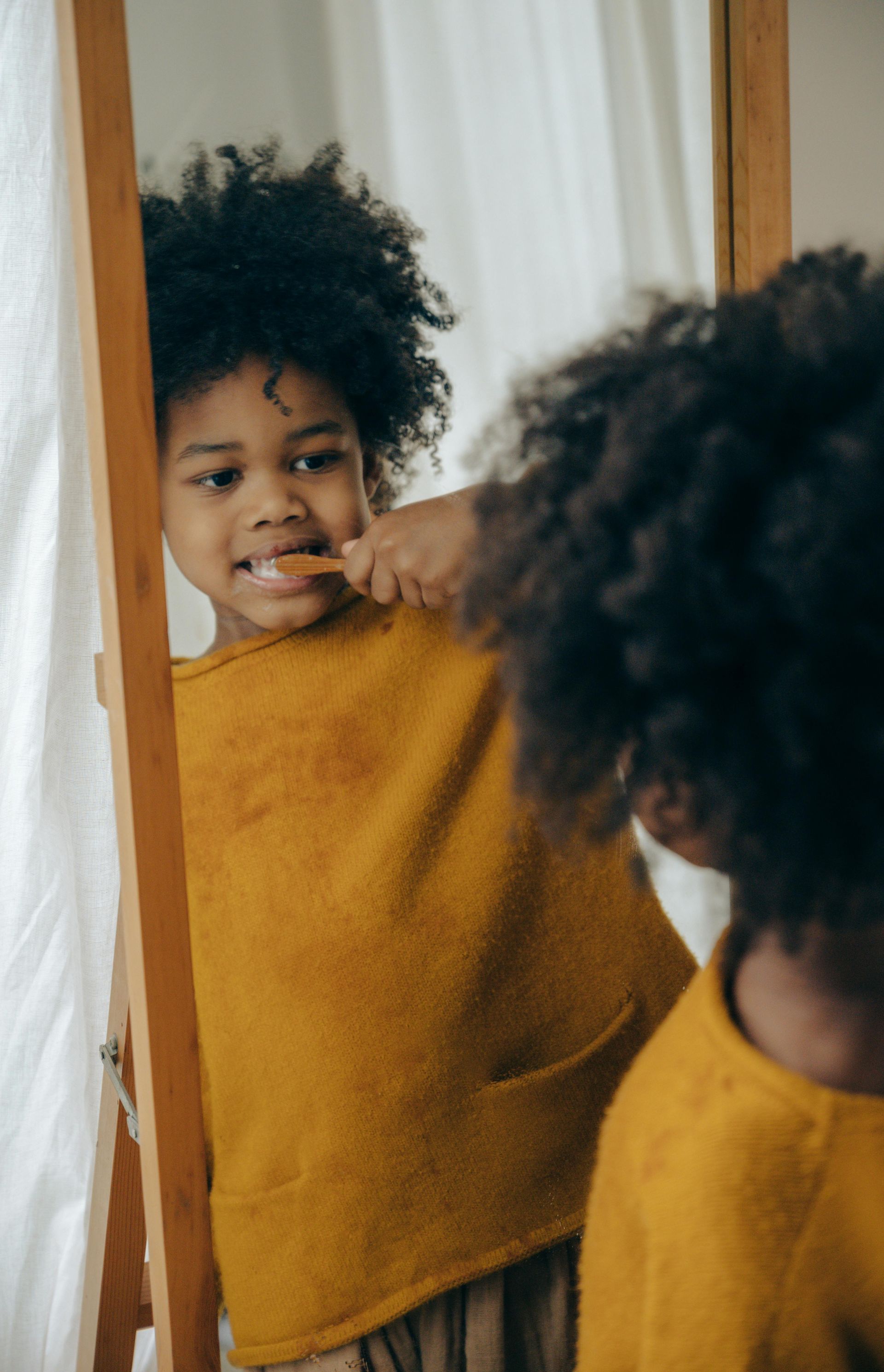 A young boy is brushing his teeth in front of a mirror.