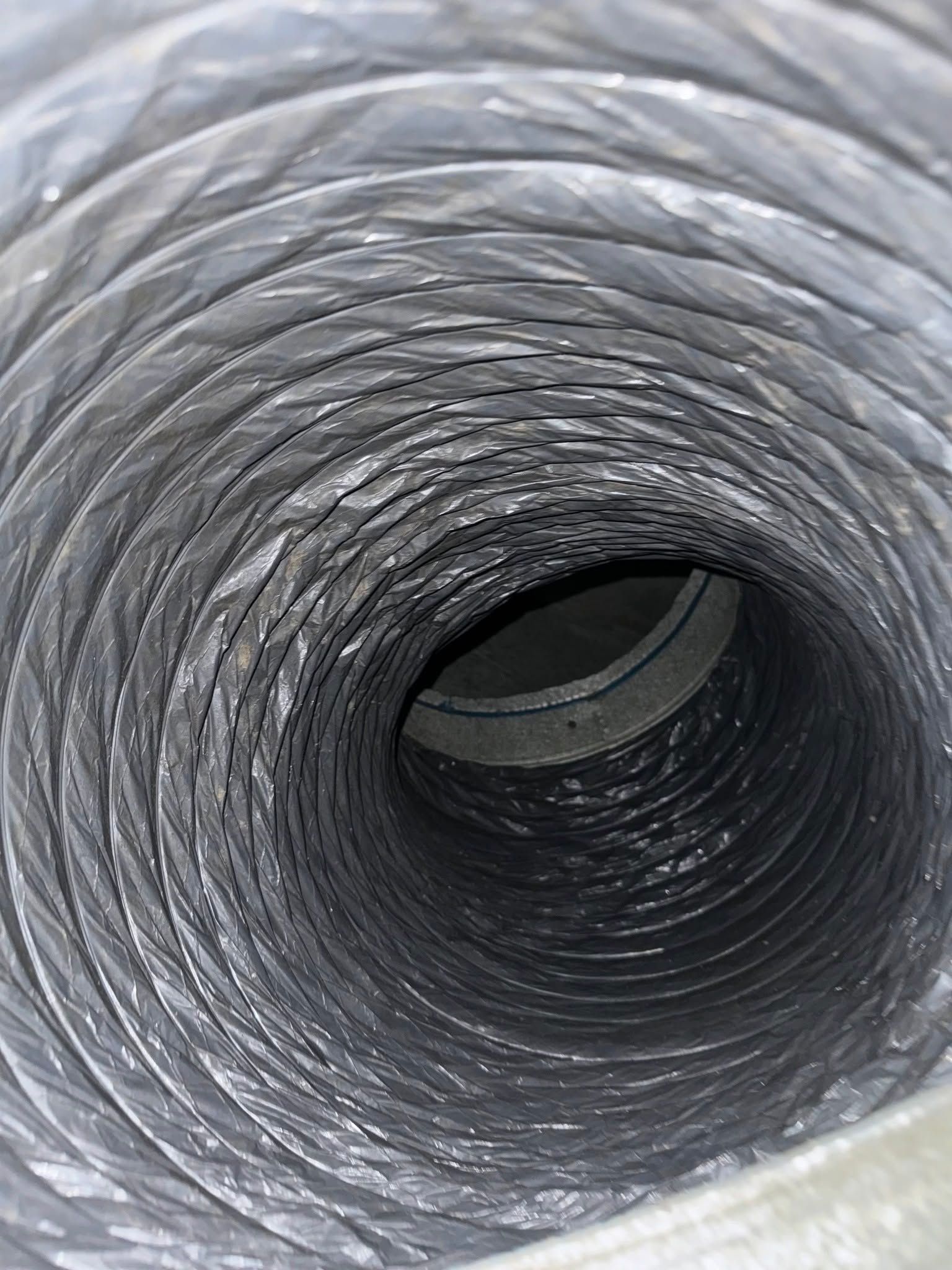 Inside a gray corrugated duct or pipe, viewed from the open end