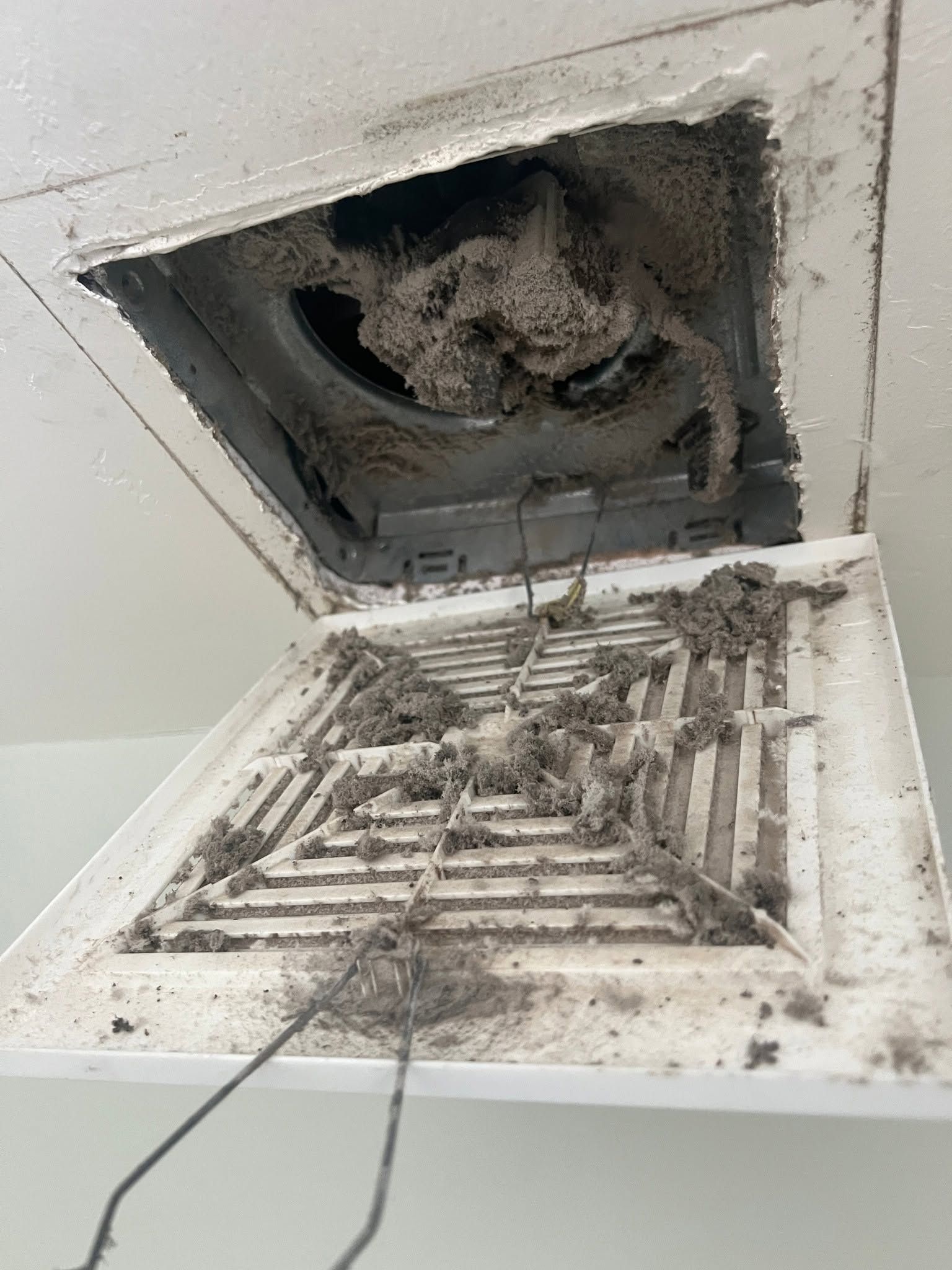 Open ceiling vent with detached grille and heavy dust buildup