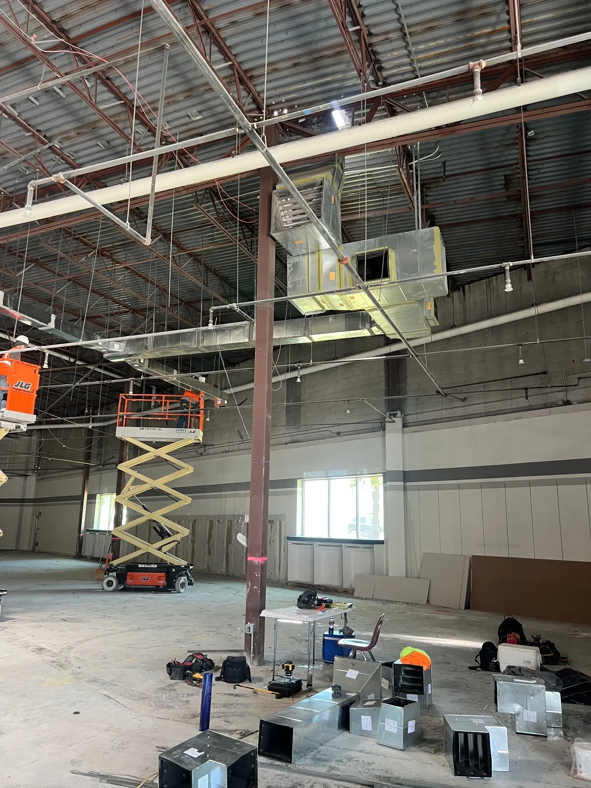 Partially constructed interior with scaffolding, hanging work platform, and tools on the floor
