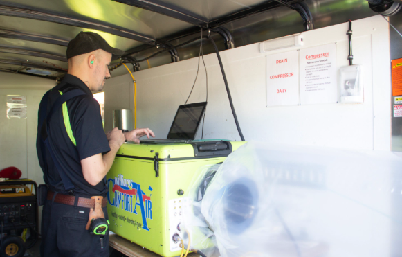 Man in dark uniform using a green cooler inside a delivery van