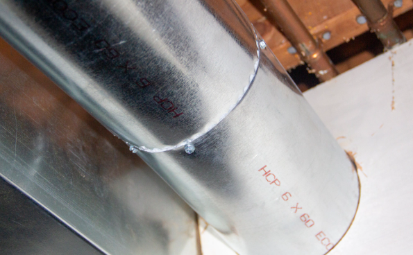 Metal ductwork with a white insulated pipe section in an industrial ceiling space