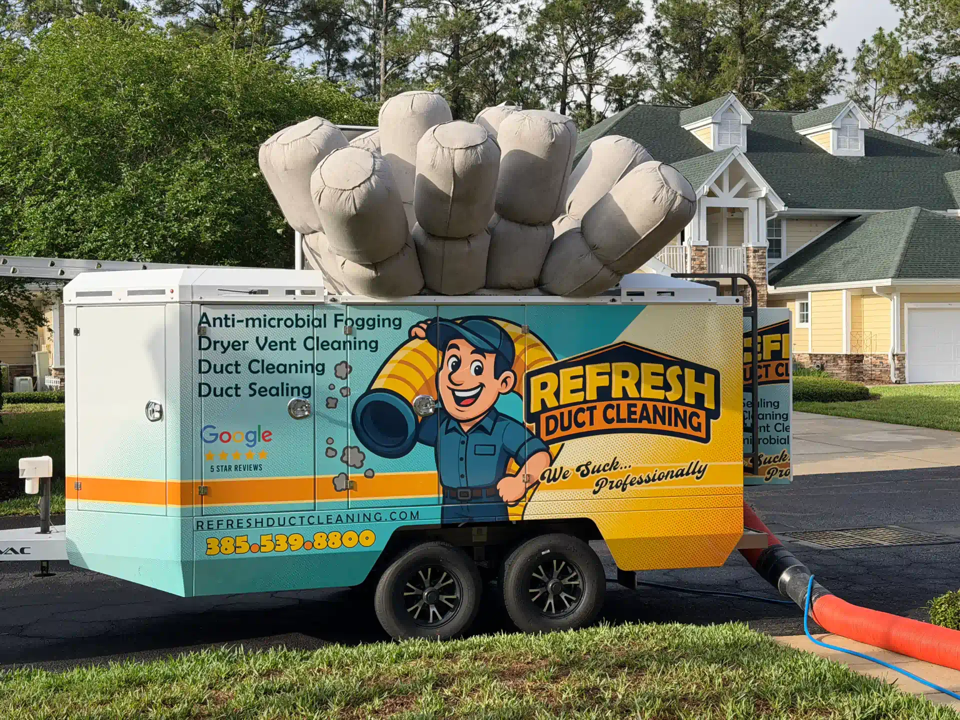 Bright orange duck-cleaning trailer with cartoon duck logo, parked beside a giant inflatable duck hand.