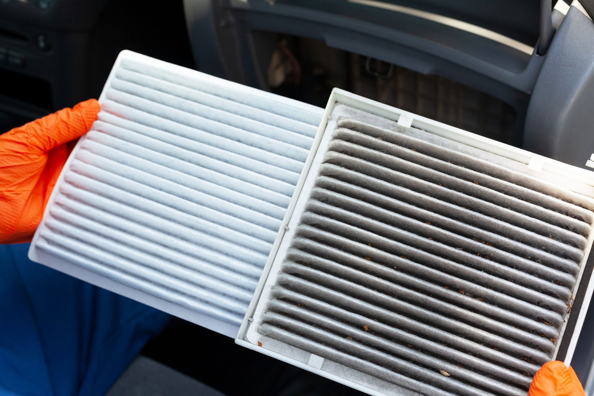 Hands holding a clean and a dirty pleated cabin air filter side by side