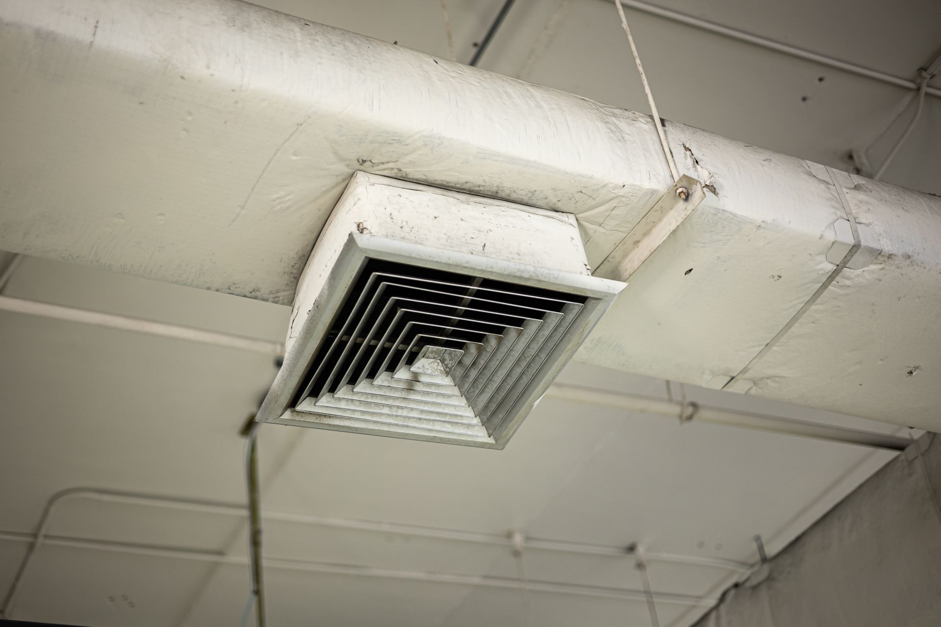 Ceiling air vent with damaged, bent metal slats in an industrial interior