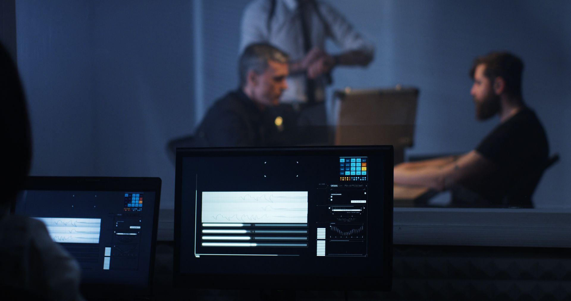A group of people are sitting at a table in front of a computer screen.