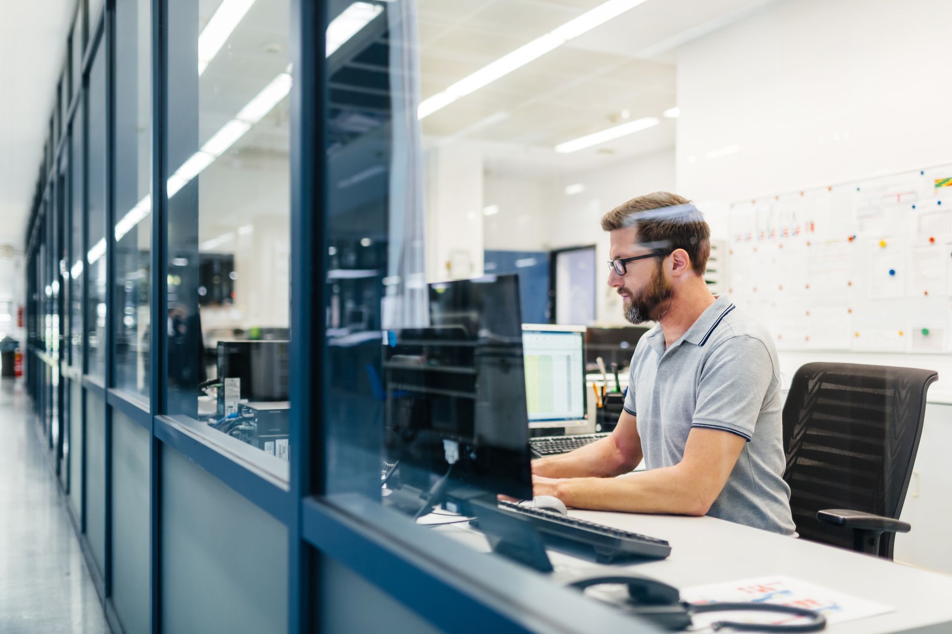 A man is sitting at a desk in front of a computer in an office.