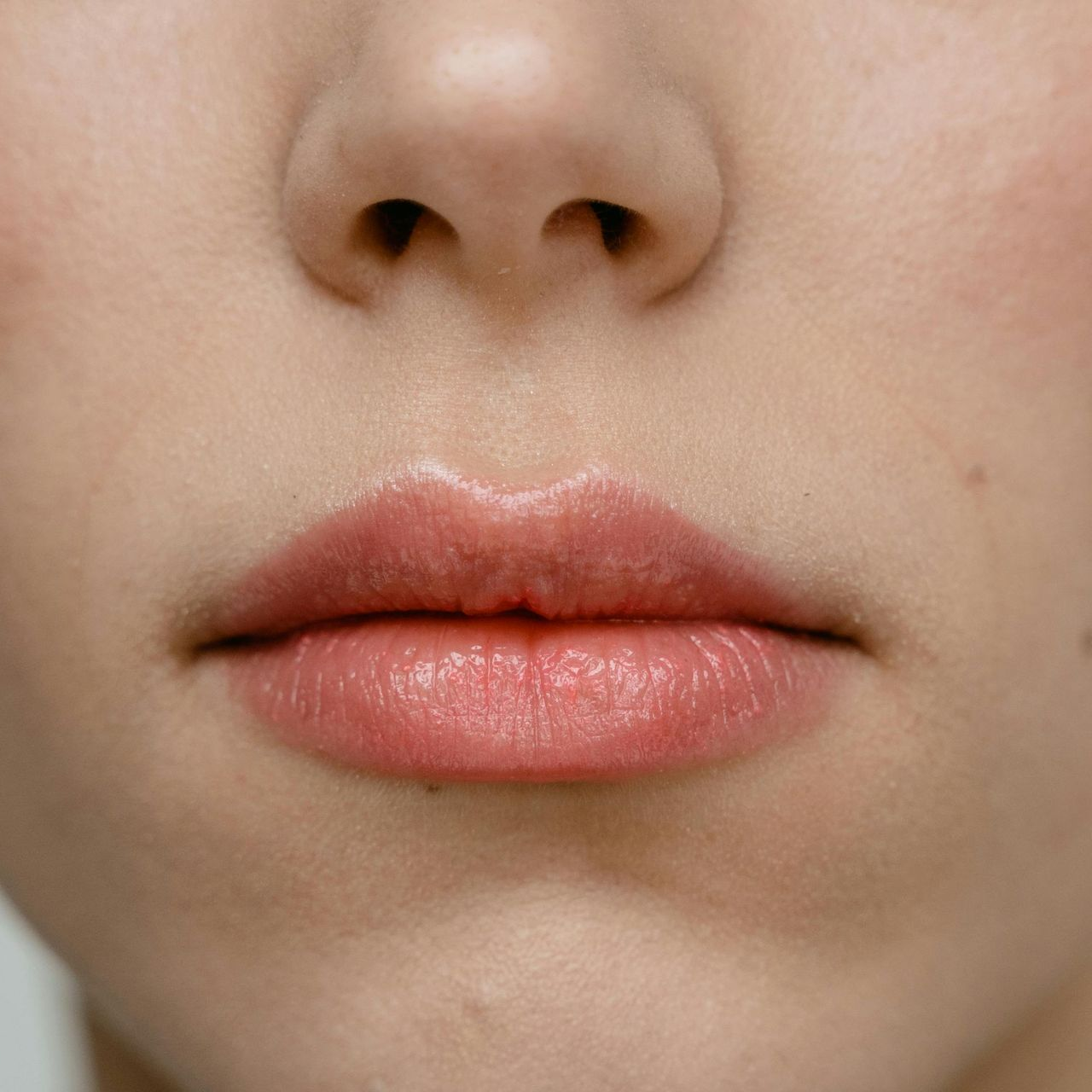 Primer plano del rostro de una persona, con énfasis en sus labios de color rosa claro. 
