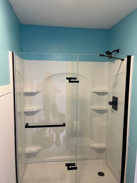 A bathroom with a walk in shower with a glass door